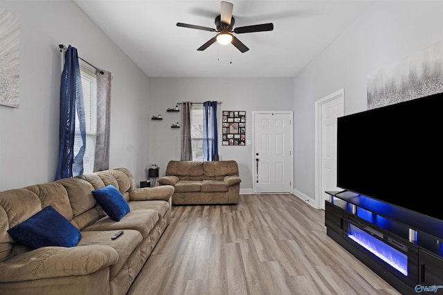 living area with ceiling fan, baseboards, wood finished floors, and a healthy amount of sunlight