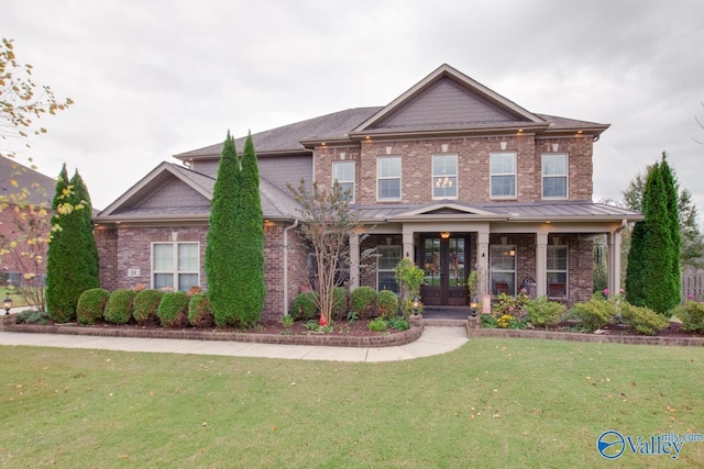 craftsman-style home with french doors, a standing seam roof, a front yard, and brick siding