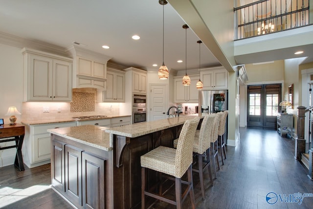 kitchen featuring dark wood-style floors, light stone counters, backsplash, and a spacious island