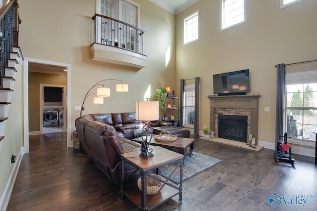 living room with a fireplace, washing machine and clothes dryer, ornamental molding, a healthy amount of sunlight, and wood finished floors