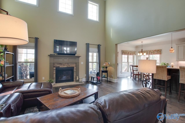 living area with a notable chandelier, a stone fireplace, wood finished floors, and a healthy amount of sunlight