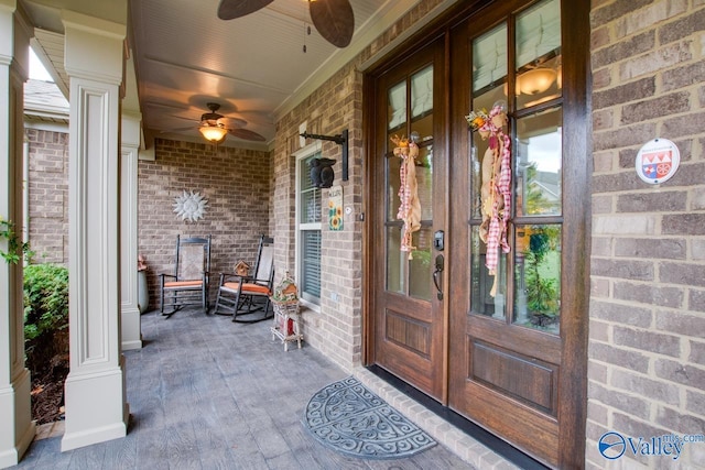 entrance to property featuring a ceiling fan, covered porch, and brick siding