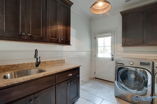 clothes washing area with washing machine and dryer, a sink, ornamental molding, wainscoting, and cabinet space