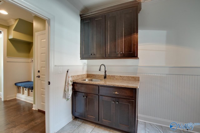 kitchen featuring a sink, dark brown cabinetry, and light stone countertops