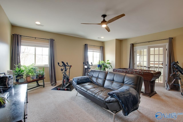 living room with a ceiling fan, french doors, light colored carpet, and baseboards