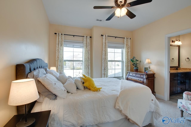 bedroom with light carpet, baseboards, visible vents, ceiling fan, and ensuite bathroom