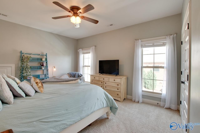 bedroom with a ceiling fan, light colored carpet, visible vents, and baseboards