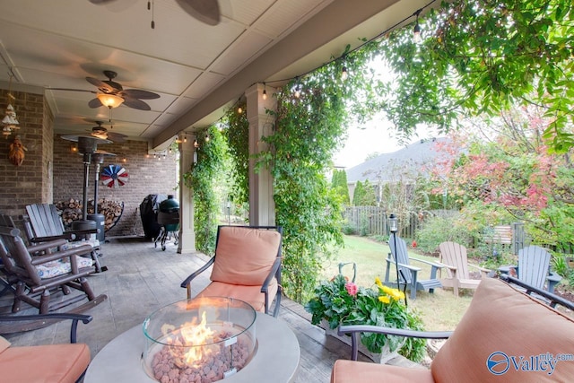 view of patio / terrace featuring a fire pit, a ceiling fan, area for grilling, fence, and a mountain view