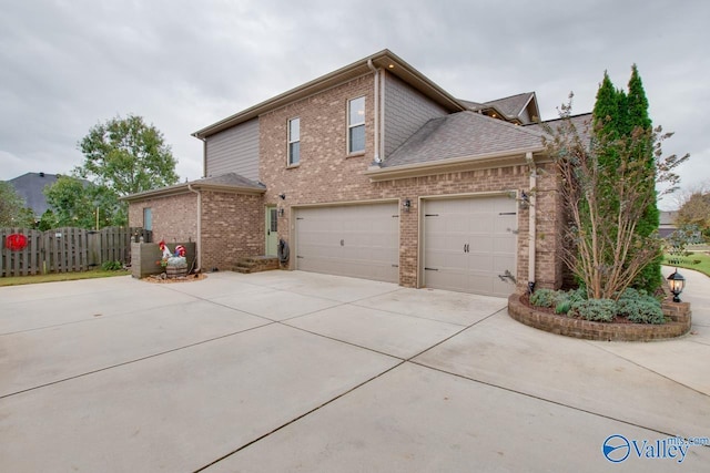 view of front facade featuring driveway, brick siding, a shingled roof, and fence