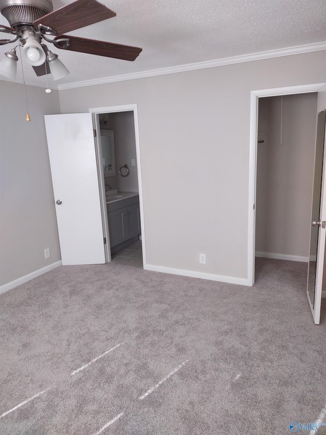 unfurnished bedroom with connected bathroom, a textured ceiling, ornamental molding, carpet floors, and a sink