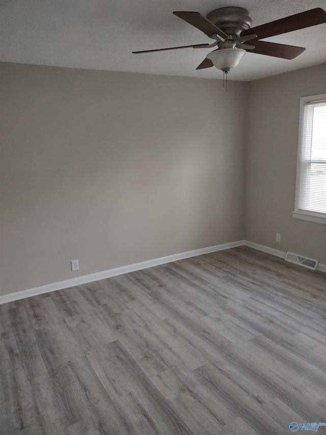 spare room with visible vents, baseboards, a ceiling fan, and wood finished floors