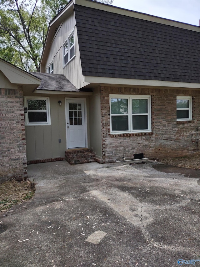 view of front of home with brick siding, roof with shingles, and entry steps