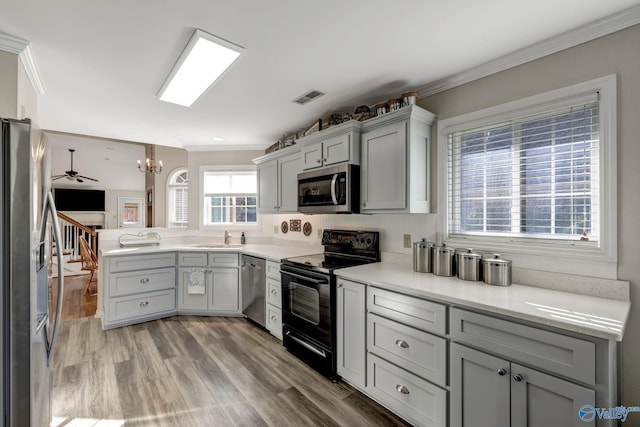 kitchen featuring stainless steel appliances, crown molding, gray cabinets, and light wood-type flooring