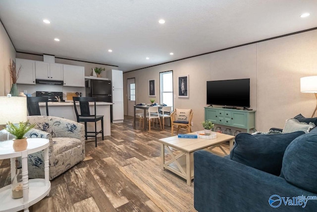 living area featuring ornamental molding, wood finished floors, and recessed lighting