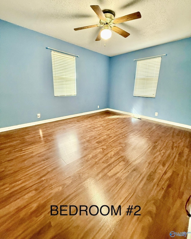 unfurnished room with hardwood / wood-style flooring, ceiling fan, a textured ceiling, and a wealth of natural light