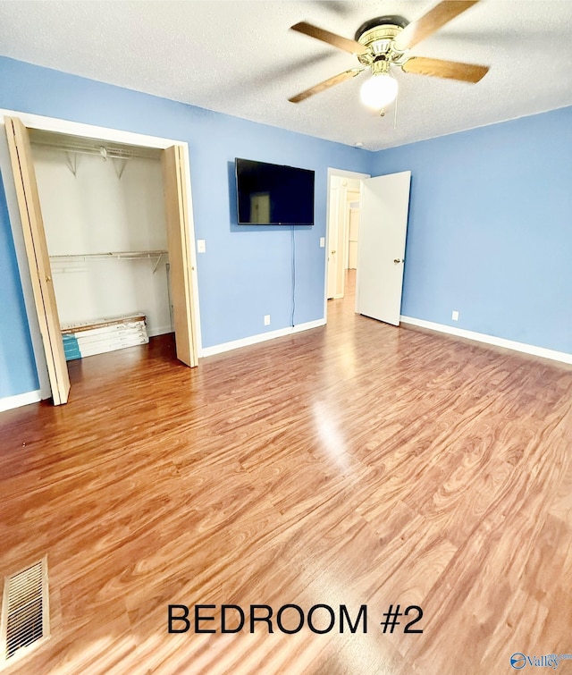 unfurnished bedroom featuring ceiling fan, light hardwood / wood-style flooring, a closet, and a textured ceiling