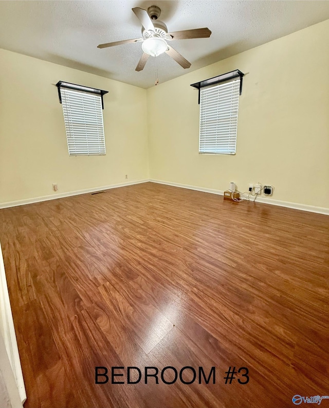 empty room with ceiling fan, hardwood / wood-style flooring, and a textured ceiling