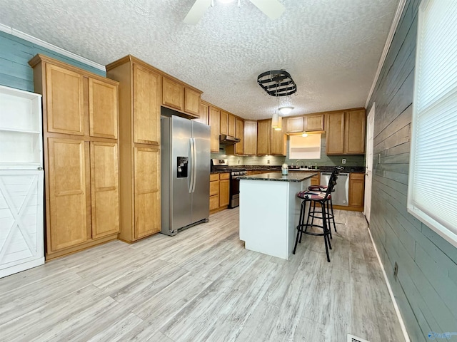 kitchen with stainless steel appliances, a kitchen breakfast bar, a kitchen island, light wood-type flooring, and wood walls