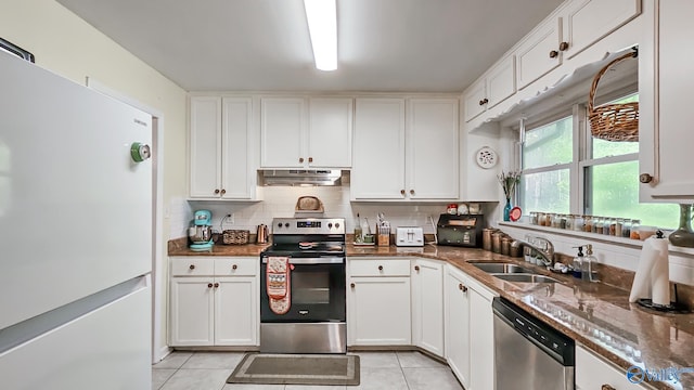 kitchen with white cabinets, appliances with stainless steel finishes, light tile patterned flooring, and sink