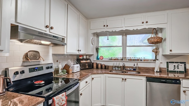 kitchen featuring appliances with stainless steel finishes, tasteful backsplash, sink, dark stone countertops, and white cabinets