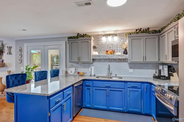 kitchen with light stone countertops, sink, appliances with stainless steel finishes, and kitchen peninsula