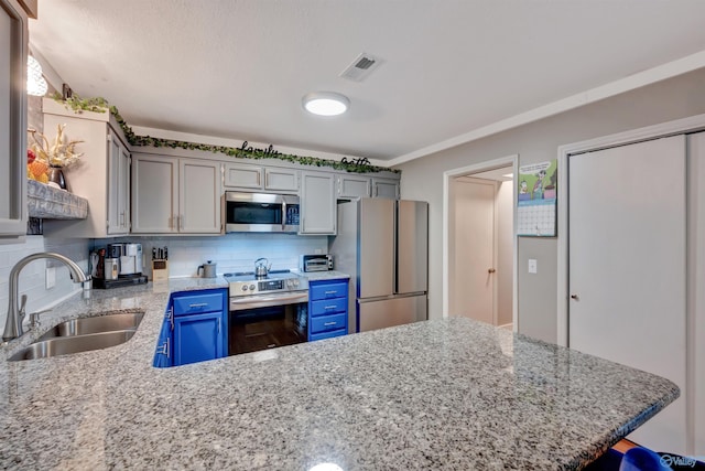 kitchen featuring appliances with stainless steel finishes, decorative backsplash, blue cabinetry, light stone countertops, and sink