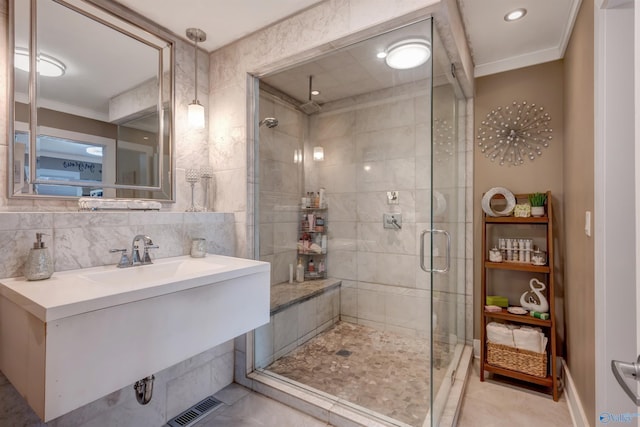 bathroom with sink, tile walls, backsplash, walk in shower, and crown molding