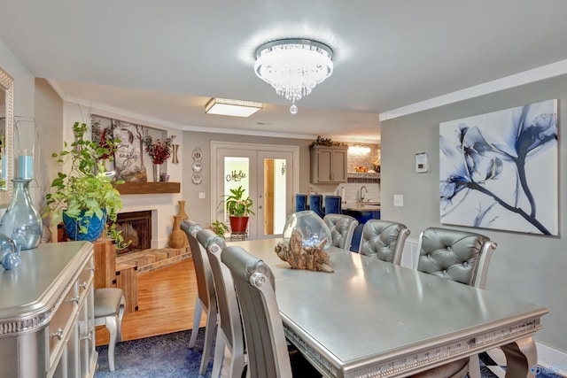 dining space featuring dark hardwood / wood-style floors, a notable chandelier, a fireplace, crown molding, and sink