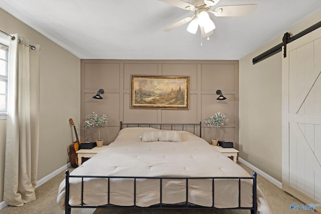 bedroom featuring baseboards, a barn door, carpet floors, and a ceiling fan