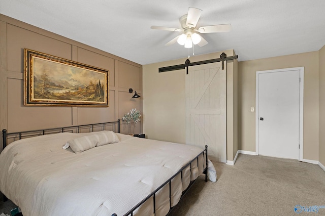 bedroom featuring baseboards, a barn door, ceiling fan, and light colored carpet