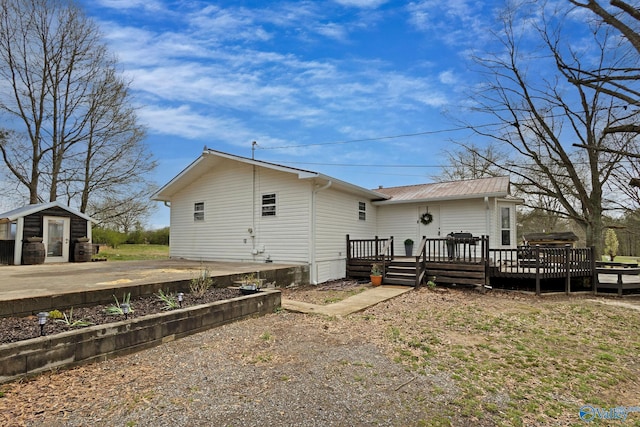 back of property featuring an outdoor structure, a shed, and a wooden deck
