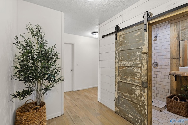interior space with wood finished floors, a textured ceiling, wood walls, and walk in shower