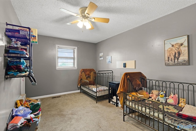 bedroom featuring carpet flooring, a textured ceiling, visible vents, baseboards, and a ceiling fan