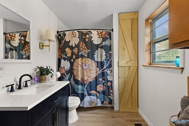 bathroom with a shower with shower curtain, toilet, vanity, wood finished floors, and baseboards