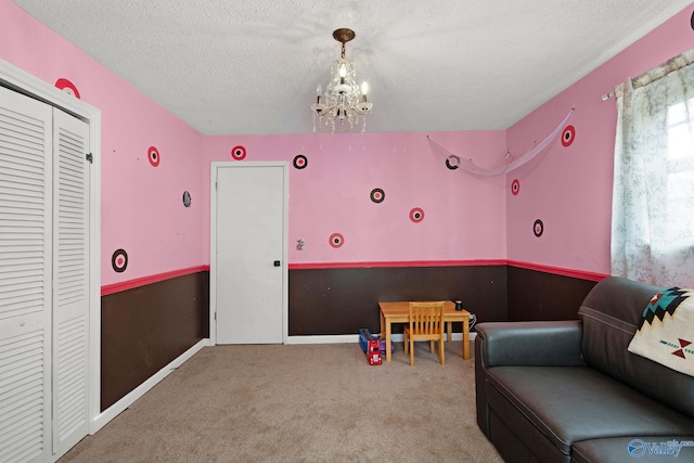 playroom with a textured ceiling, an inviting chandelier, and carpet