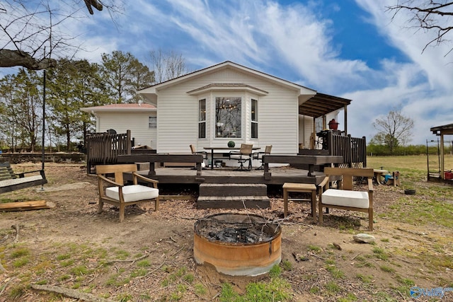 back of property with a fire pit and a wooden deck