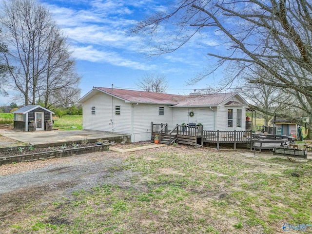 back of property with an outbuilding, metal roof, and a deck