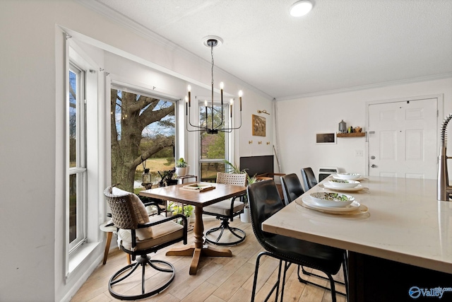 dining space with a textured ceiling, light wood-style flooring, ornamental molding, and an inviting chandelier