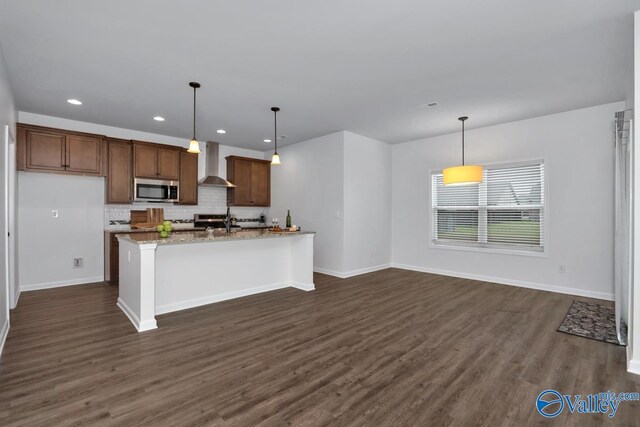 kitchen featuring decorative light fixtures, stainless steel appliances, dark wood-type flooring, and wall chimney range hood