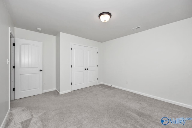 unfurnished bedroom featuring a closet and light colored carpet