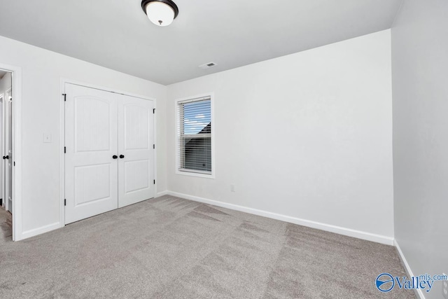 unfurnished bedroom with a closet and light colored carpet