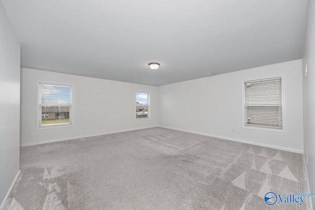 spare room featuring light carpet and plenty of natural light