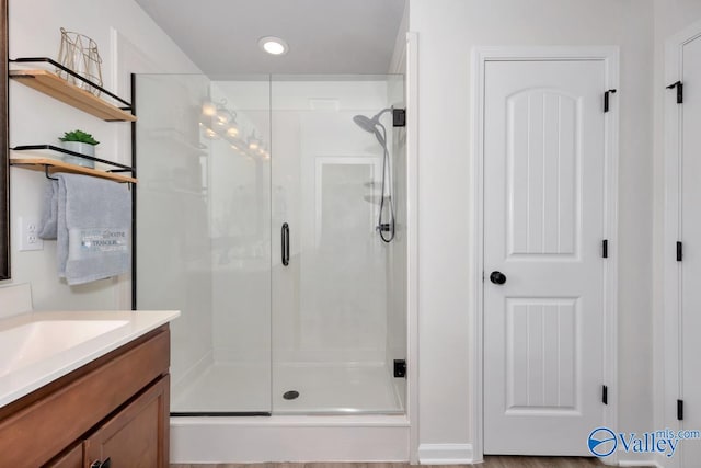 bathroom with hardwood / wood-style floors, vanity, and walk in shower