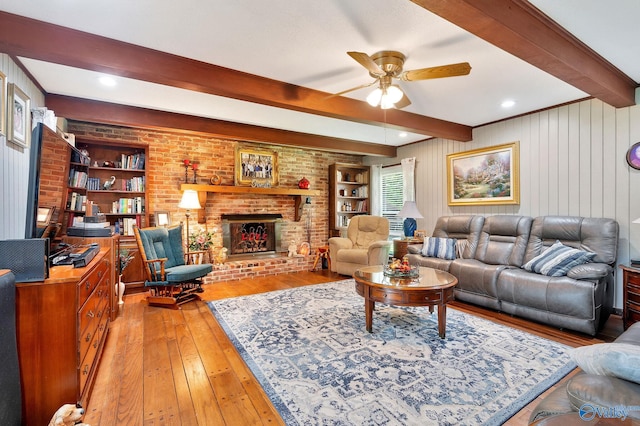 living room featuring a fireplace, ceiling fan, brick wall, beam ceiling, and light hardwood / wood-style floors