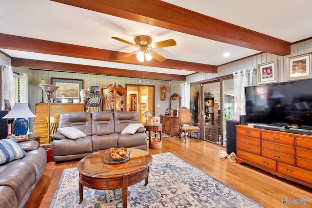 living room featuring beamed ceiling, light hardwood / wood-style flooring, and ceiling fan