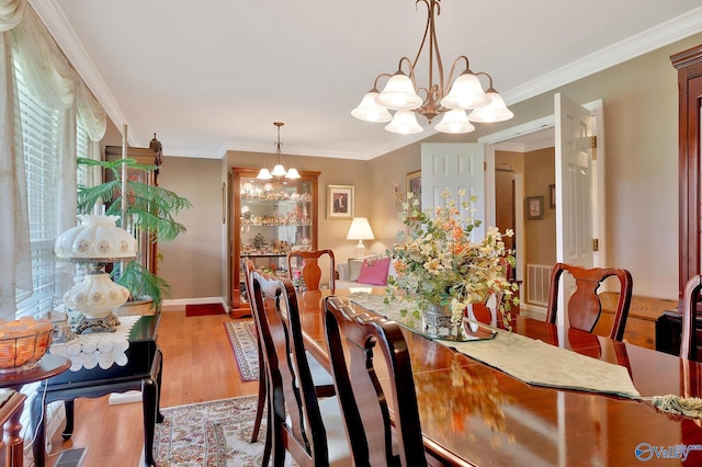dining room with hardwood / wood-style flooring, a notable chandelier, and crown molding