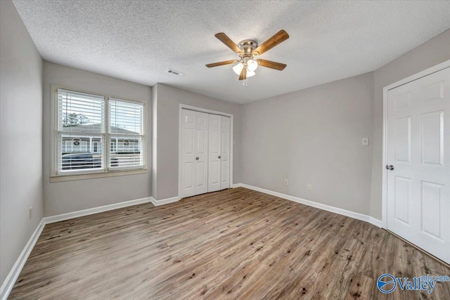 unfurnished bedroom featuring ceiling fan, a closet, a textured ceiling, and light wood-type flooring