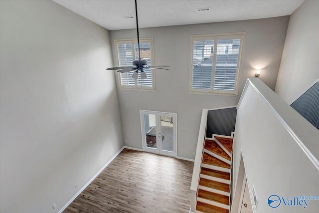 stairway featuring hardwood / wood-style flooring, ceiling fan, and a textured ceiling