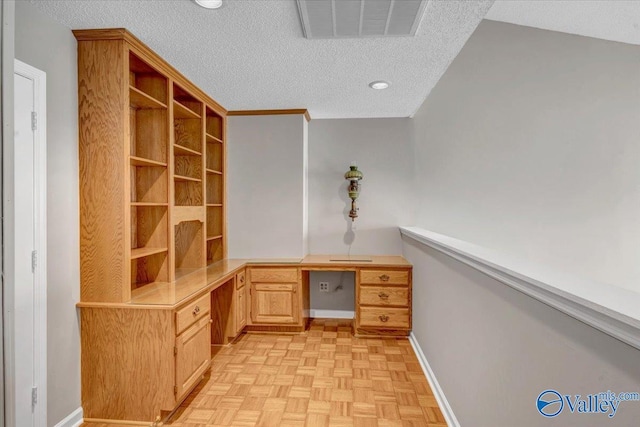 unfurnished office with a textured ceiling, built in desk, lofted ceiling, and light parquet flooring