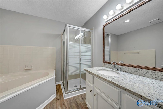 bathroom with hardwood / wood-style flooring, vanity, shower with separate bathtub, and a textured ceiling